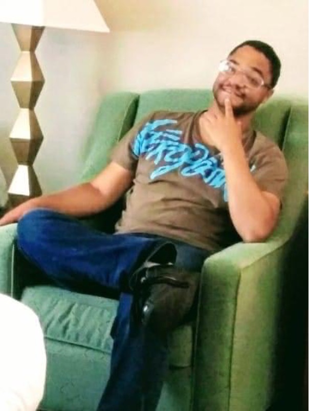 Photo of Joshua De’Miguel Kavota sitting on green couch