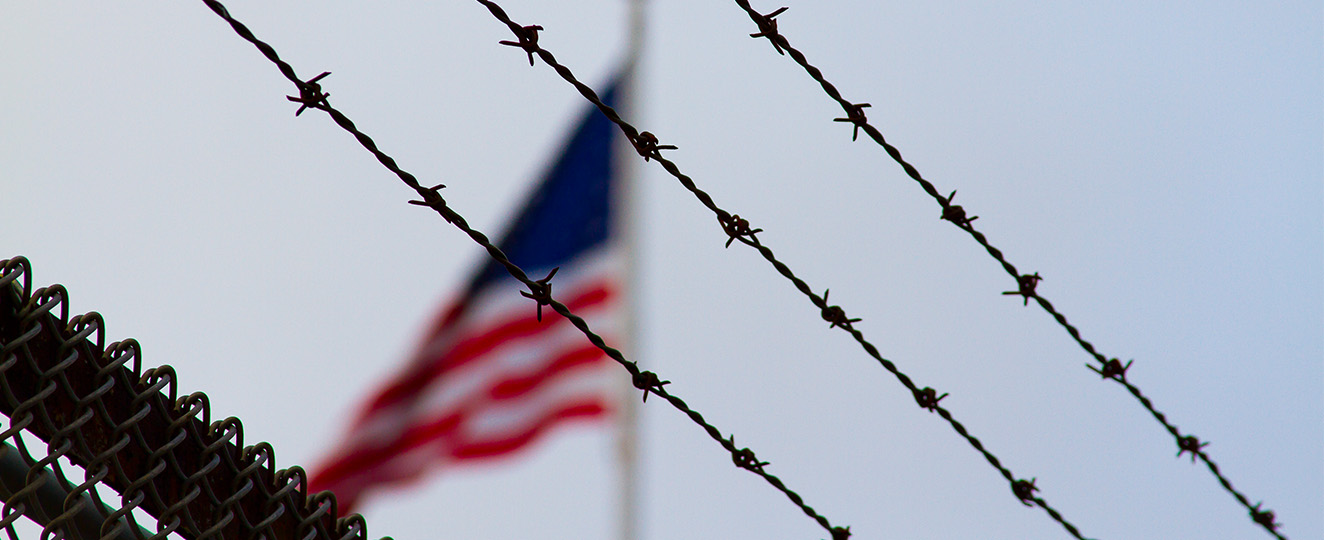 American flag behind barbed wire.