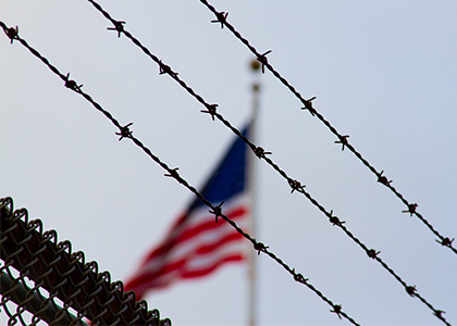 American flag behind barbed wire.